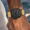Accessoire homme au design innovant : montre DOM avec cadran noir texturé et bracelet en cuir jaune.