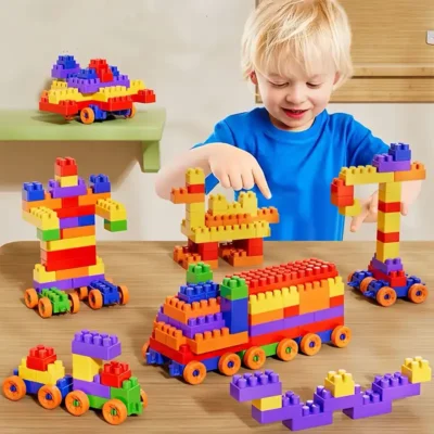 Petit garçon souriant en train de construire avec des blocs colorés — jeu éducatif qui développe motricité fine, concentration et créativité dès 3 ans.