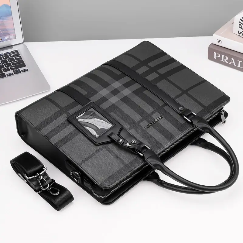Sac business en cuir pour homme, avec motif carreaux gris, posé sur un bureau avec ordinateur portable — idéal pour les professionnels en déplacement ou au travail.