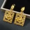 Boucles d’oreilles dorées avec motif fleur sculptée dans un cadre ajouré — finition délicate et raffinée, idéale pour un look de mariage ou cérémonie.
