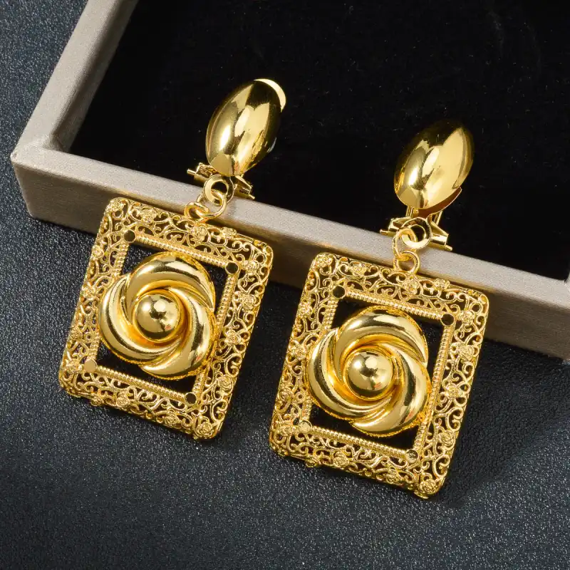 Boucles d’oreilles dorées avec motif fleur sculptée dans un cadre ajouré — finition délicate et raffinée, idéale pour un look de mariage ou cérémonie.