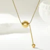 Collier en acier inoxydable doré avec pendentif bille et barre pendante — finition brillante et design épuré, idéal pour sublimer une tenue sobre ou habillée.