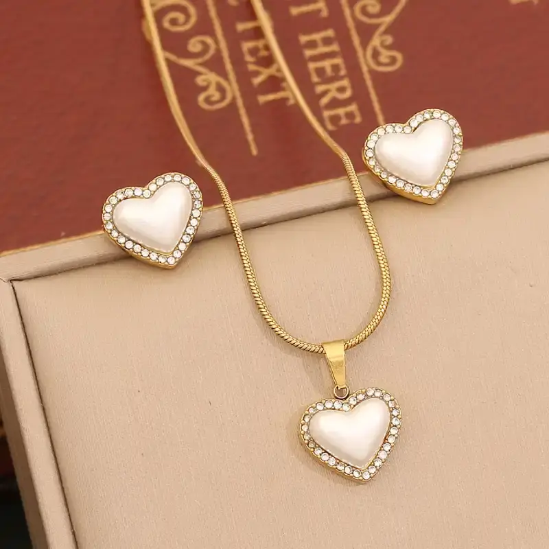 Ensemble bijoux d’amour en forme de cœur : collier et boucles d’oreilles avec perle nacrée entourée de strass — idéal pour une touche romantique et élégante.