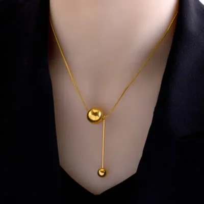 Collier en acier inoxydable doré avec pendentif boule ronde et barre verticale — design minimaliste et élégant, parfait pour un look moderne et sophistiqué.
