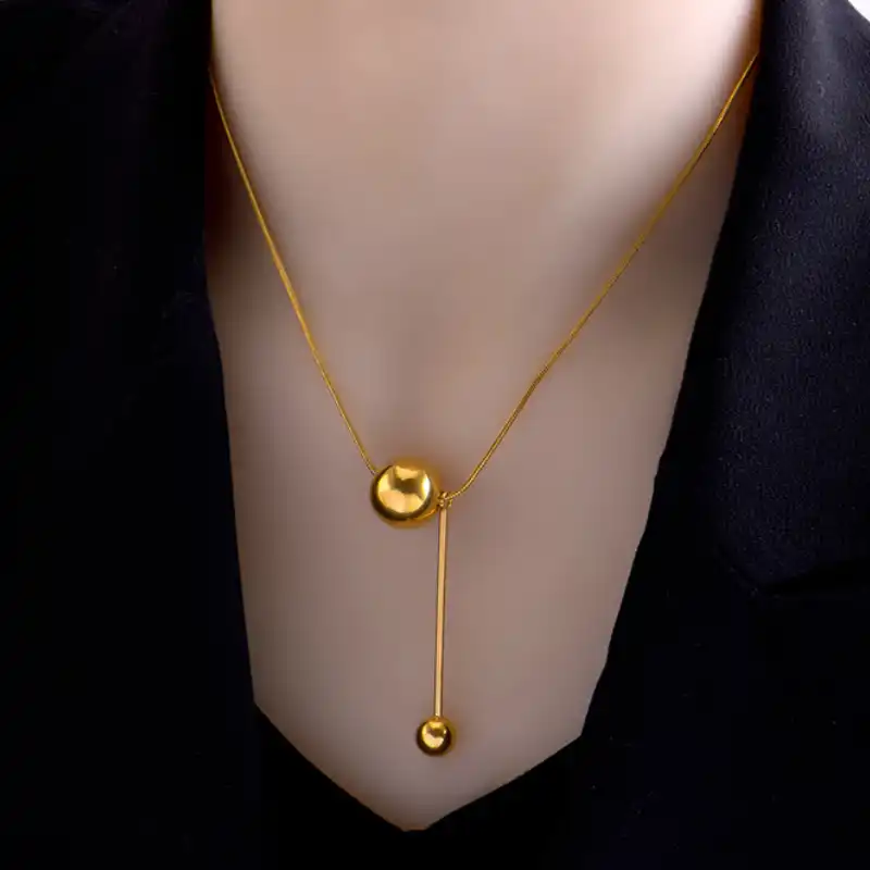 Collier en acier inoxydable doré avec pendentif boule ronde et barre verticale — design minimaliste et élégant, parfait pour un look moderne et sophistiqué.
