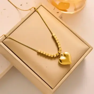 Collier doré avec pendentif cœur et perles carrées, présenté dans une boîte cadeau beige — idéal comme présent pour elle, à l’occasion d’un anniversaire, la Saint-Valentin ou la fête des mères.