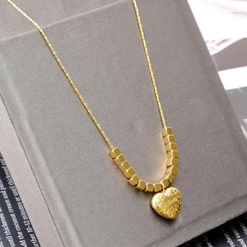 Collier fin en or avec pendentif cœur gravé « Love » et perles carrées — présenté sur un support élégant, idéal comme cadeau pour elle, pour la Saint-Valentin ou une déclaration d’amour.