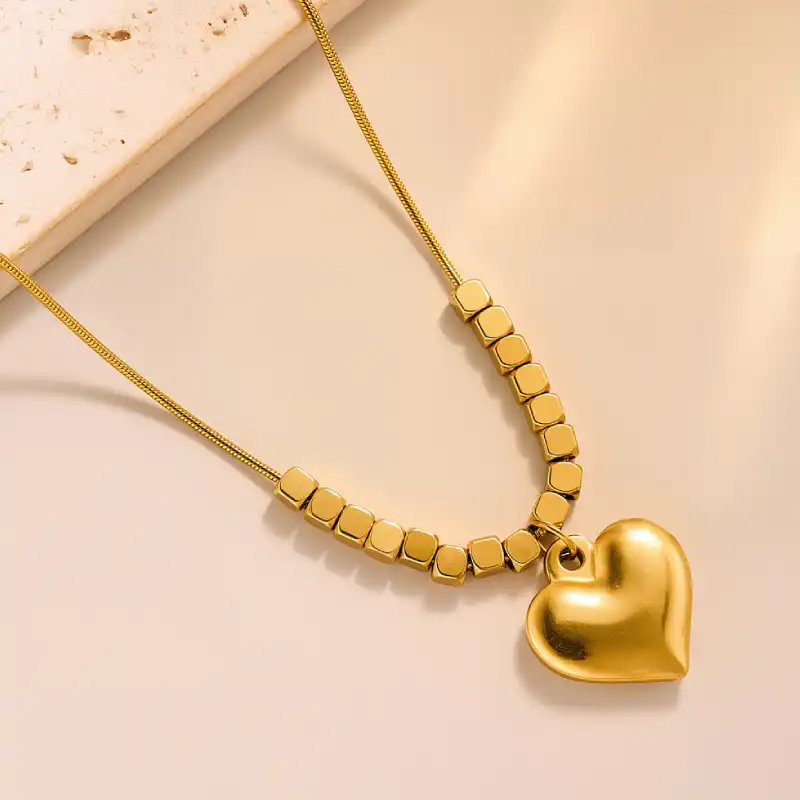 Collier tendance en or avec pendentif cœur lisse et chaîne ornée de perles cubiques — design moderne et élégant, parfait pour un look quotidien ou une occasion spéciale.