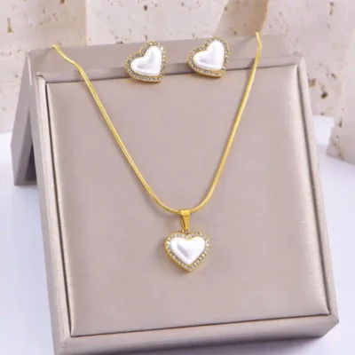Collier et boucles d’oreilles en forme de cœur avec perle blanche et bordure de strass, présentés sur un présentoir — cadeau parfait pour la Saint-Valentin, un anniversaire ou une fête des mères.