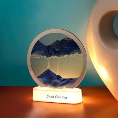 Lampe sable mouvant 3D allumée en LED chaude, révélant un paysage montagneux bleu avec paillettes dorées — effet visuel hypnotique et apaisant pour la méditation ou le sommeil.