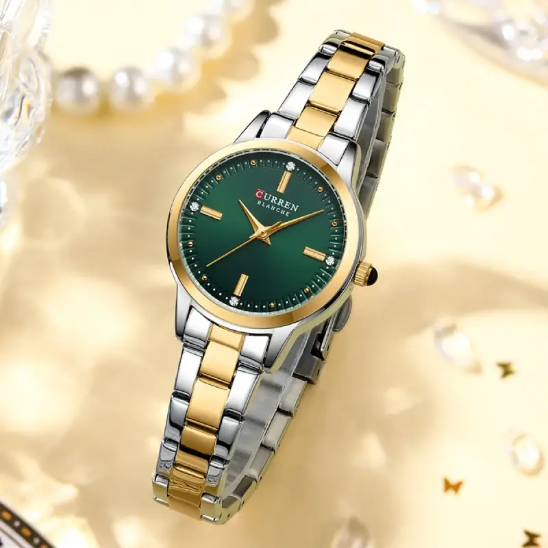 Montre femme Curren 9094 dans une mise en scène luxueuse : fond doré, perles et reflets lumineux — souligne l’élégance et la qualité du bracelet bicolore et du cadran vert émeraude.