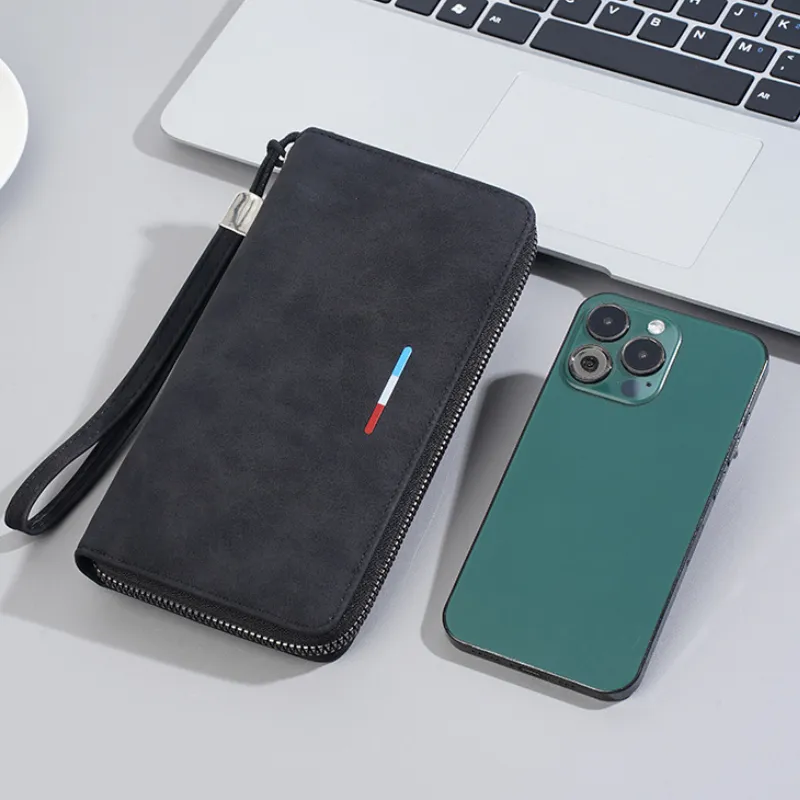 Portefeuille homme long noir zippé, posé à côté d’un smartphone vert et d’un MacBook — démontre sa capacité à ranger téléphone, cartes et billets dans un format élégant et compact.