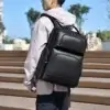 Homme portant le sac à dos noir haut de gamme en extérieur, vue arrière montrant l'ajustement des bretelles et le style urbain moderne.