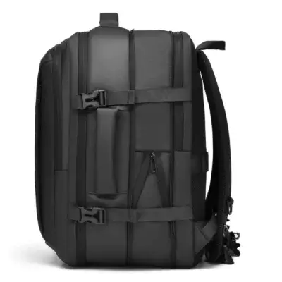 Côté du sac à dos de voyage noir montrant les boucles de serrage, la poignée de transport horizontale et la texture du tissu Oxford.