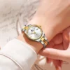 Montre femme OLEVS 3621 portée au poignet, bracelet acier inoxydable bicolore or et argent, cadran blanc avec cristaux étincelants — accessoire élégant pour tenue de ville ou soirée.
