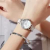 Femme portant la montre OLEVS 5656 au poignet, accessoire de mode féminin en acier argenté brillant, idéal pour un look chic et sophistiqué.