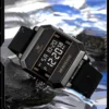 Montre sport OLEVS 1103 noire posée sur un rocher mouillé avec éclaboussures d'eau, démontrant son étanchéité 30M et son design robuste pour activités de plein air.