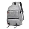 Vue de face du sac à dos gris grande capacité sur fond blanc, montrant les multiples compartiments zippés, les poches latérales en mesh respirant et les sangles de compression à boucles.