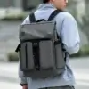 Homme portant le sac à dos gris grande capacité sur le dos en extérieur, montrant le confort des bretelles larges et le style décontracté urbain — sac à dos imperméable parfait pour les trajets quotidiens et le transport d'ordinateur 16 pouces.