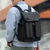 Vue arrière d'un homme portant le sac à dos noir roll-top avec poches avant multiples et boucles de serrage, style streetwear moderne — sac à dos grande capacité imperméable adapté aux jeunes actifs et étudiants.