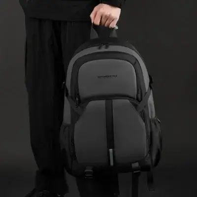 Sac à dos Wepower Style gris et noir tenu par la poignée supérieure, montrant les multiples poches zippées, les poches latérales et les sangles réglables — accessoire pratique et robuste pour homme.