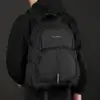 Homme portant le sac à dos Wepower Style noir sur le dos avec veste à capuche, design moderne avec bandes réfléchissantes et sangles de compression — sac imperméable grande capacité idéal pour le travail, l'université ou les déplacements urbains.