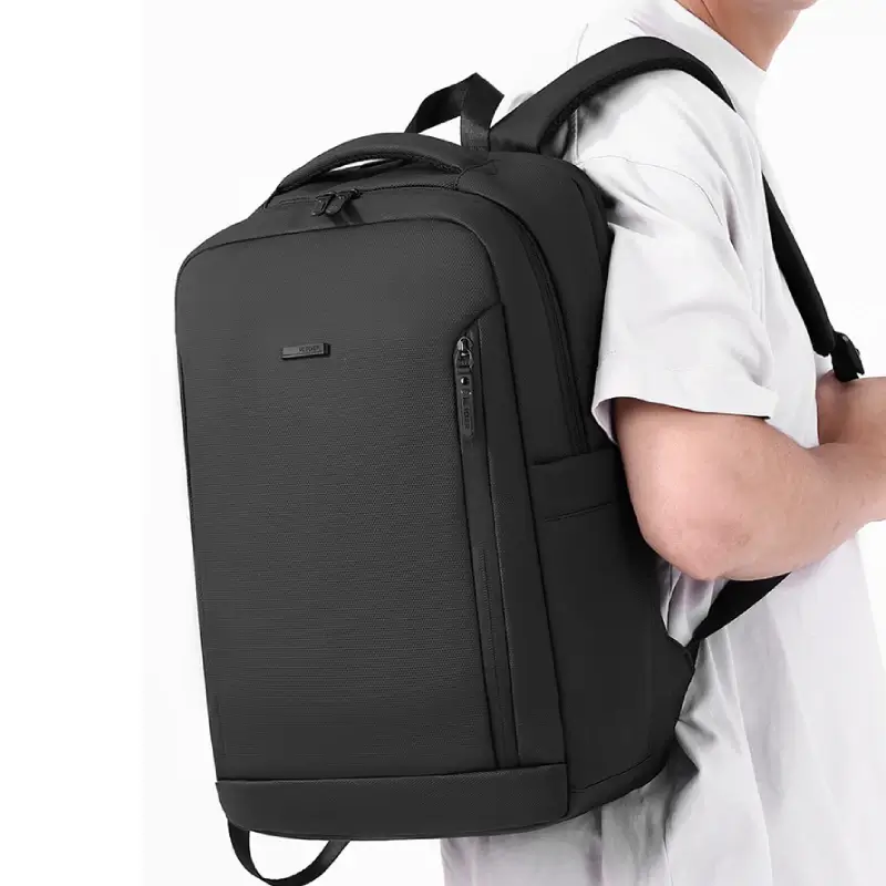 Homme portant le sac à dos business Wepower noir sur le dos, design sobre et élégant avec poche avant zippée verticale — idéal pour le travail, les déplacements et le transport d'ordinateur portable.