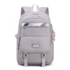 Vue de face du sac à dos scolaire fille gris JIANGLIDA sur fond blanc, montrant le design structuré avec rabat avant, boucles de serrage et bandes colorées — sac léger et imperméable parfait pour le lycée et l'université.