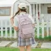 Jeune fille portant un sac à dos de lycée couleur lavande (rose pâle) vu de dos, design léger et imperméable avec multiples poches et sangles à boucles — idéal pour le collège, le lycée et les sorties quotidiennes.