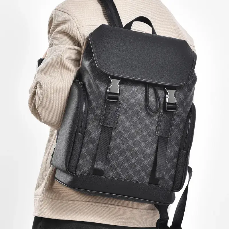 Homme portant le sac à dos voyage business noir à motif monogramme sur l'épaule, design élégant avec poches latérales zippées et sangles à boucles, idéal pour transporter un ordinateur 16 pouces au quotidien.