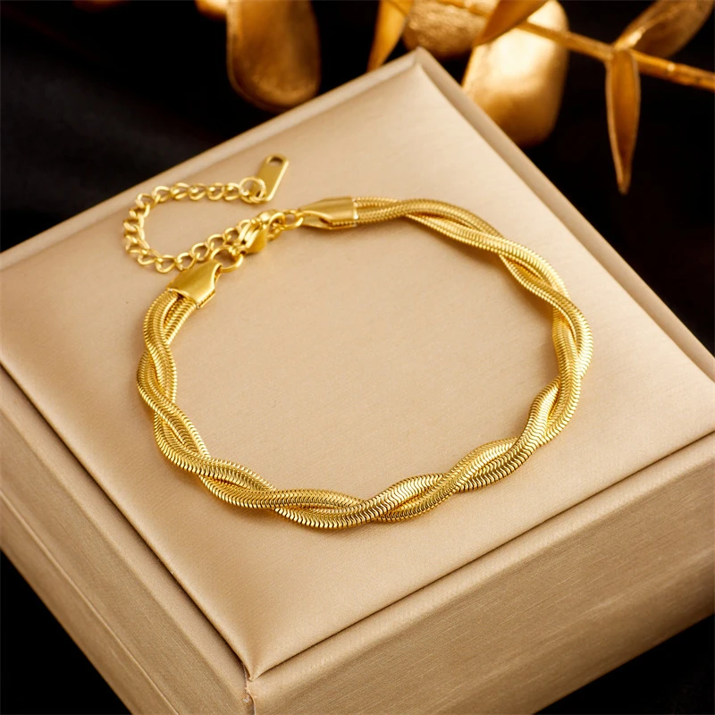 Bracelet torsadé doré style chaîne serpent posé sur un coffret à bijoux beige, montrant le fermoir sécurisé et la chaîne d'extension réglable — design tressé élégant et raffiné pour femme.