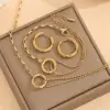 Parure complète 3 pièces dorée anti-ternissement comprenant collier à double chaîne, bracelet assorti et boucles d'oreilles créoles, tous ornés d'un motif anneau circulaire — set de bijoux femme élégant présenté sur écrin, parfait pour un cadeau.