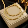 Ensemble parure collier et bracelet torsadé doré, design tressé élégant style chaîne serpent présenté sur un écrin beige — bijou femme raffiné et lumineux, idéal pour un cadeau ou une tenue de soirée.