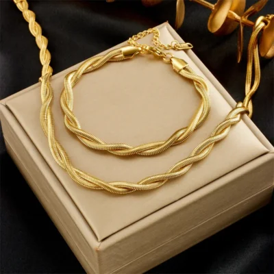 Ensemble parure collier et bracelet torsadé doré, design tressé élégant style chaîne serpent présenté sur un écrin beige — bijou femme raffiné et lumineux, idéal pour un cadeau ou une tenue de soirée.