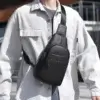 Homme portant une sacoche noire en bandoulière sur la poitrine, avec une chemise blanche.