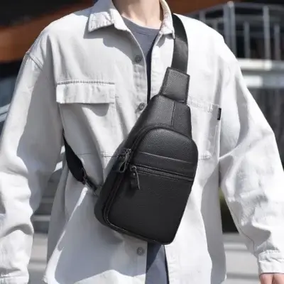 Homme portant une sacoche noire en bandoulière sur la poitrine, avec une chemise blanche.