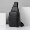 Sacoche bandoulière homme noire à texture grainée, vue de face avec poche avant zippée.