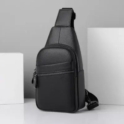 Sacoche bandoulière homme noire à texture grainée, vue de face avec poche avant zippée.