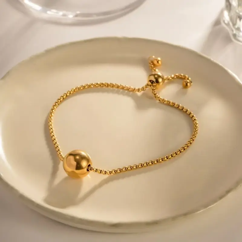 Bracelet tendance en acier inoxydable plaqué or avec chaîne à billes et perle centrale dorée, fermoir coulissant ajustable — bijou minimaliste et élégant pour femme, parfait pour un look quotidien chic.