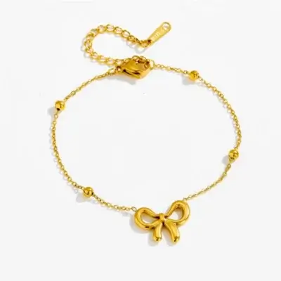 Bracelet doré tendance en acier inoxydable avec pendentif nœud papillon 3D, chaîne fine ornée de petites boules dorées et fermoir à chaîne d'extension réglable — bijou femme élégant et délicat, parfait pour un cadeau ou un look quotidien raffiné.