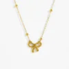 Collier femme doré avec pendentif nœud papillon en relief, chaîne fine agrémentée de perles dorées espacées — bijou minimaliste et romantique en acier inoxydable, idéal pour accessoiriser une tenue chic ou décontractée.