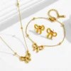Parure complète de bijoux dorés en acier inoxydable comprenant collier, bracelet et boucles d'oreilles assortis, tous ornés d'un motif nœud papillon 3D et de boules dorées sur chaîne fine — ensemble tendance et élégant pour femme, parfait en cadeau de Noël, anniversaire ou fête des mères.